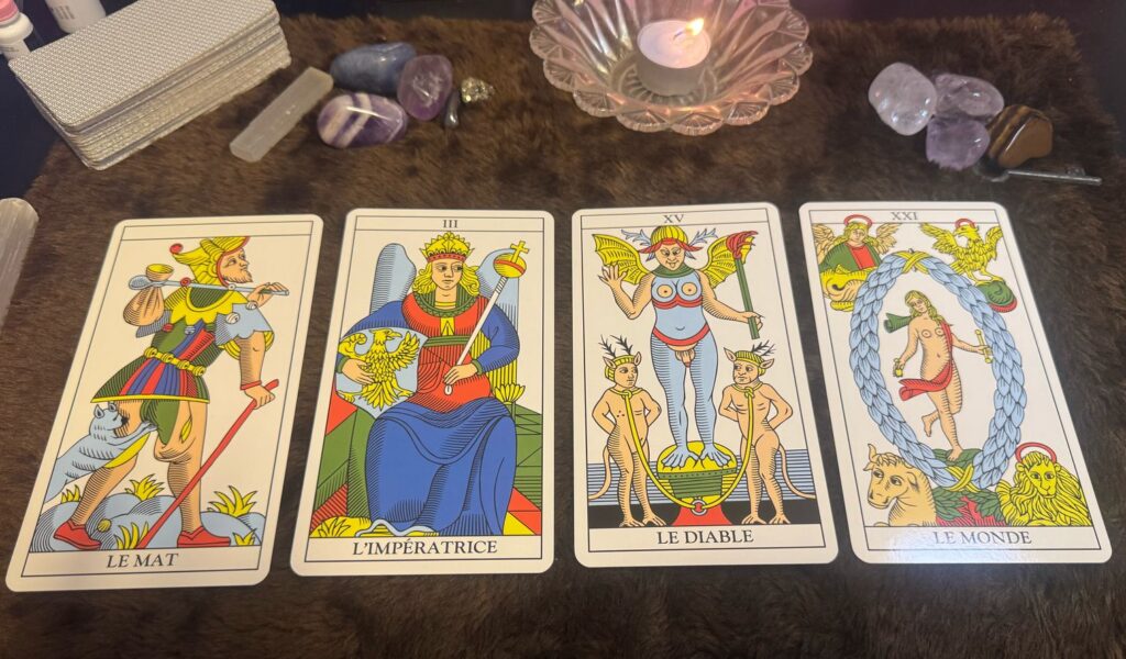Tiragem com quatro cartas representando arquétipos no tarot: O Louco, A Imperatriz, O Diabo e O Mundo sobre uma mesa ritualística.